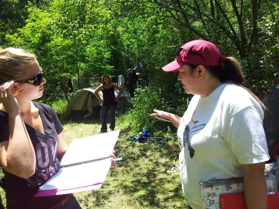 Tommy Brunswick holding a clipboard and talking with a colleague on an outdoor film set