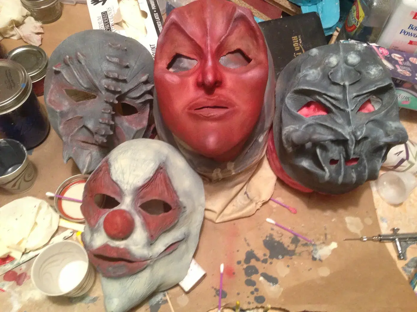 Painted creature masks, sculpting materials and supplies covering Tommy’s workbench