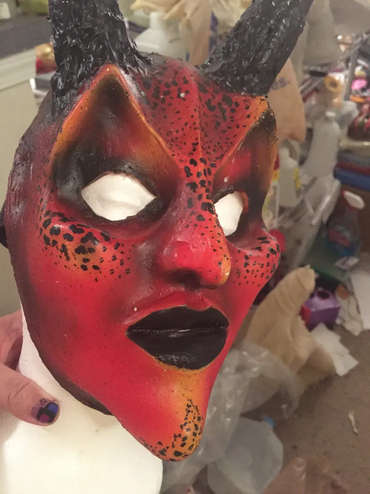 A red-and-black horned demon mask painted by Tommy Brunswick