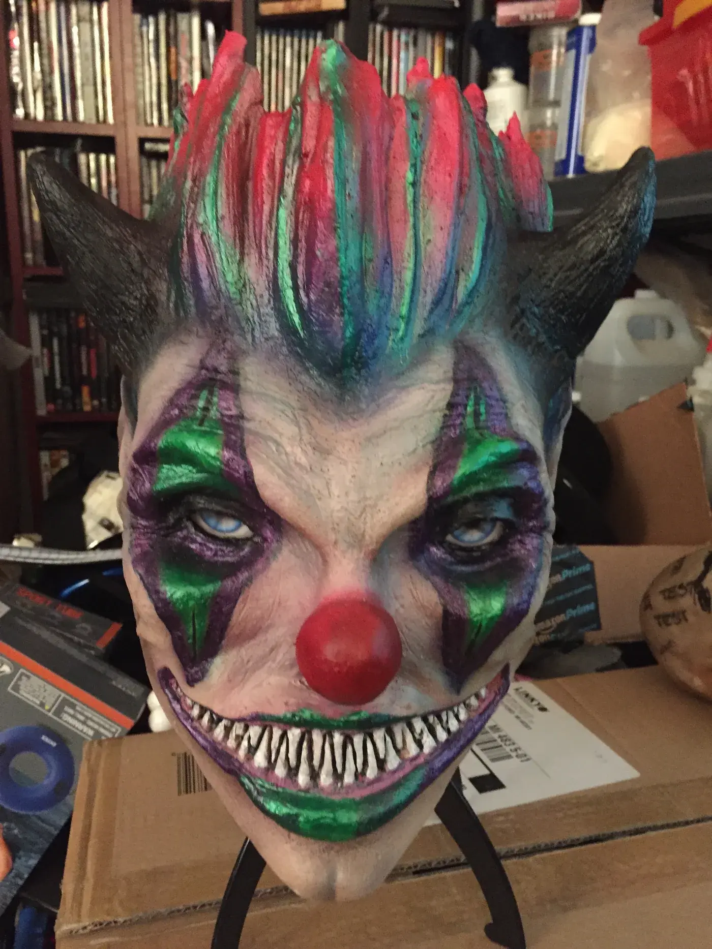 Colorful clown sculpture with tall striped hair, pointed ears and a broad toothy grin